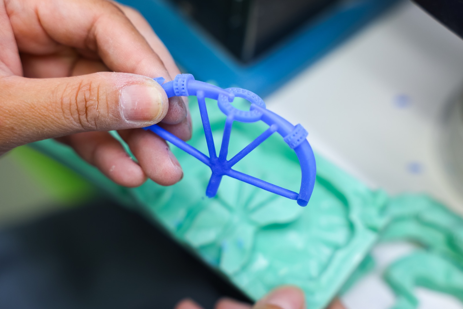 Freshly injected wax jewelry copy held above its rubber mold